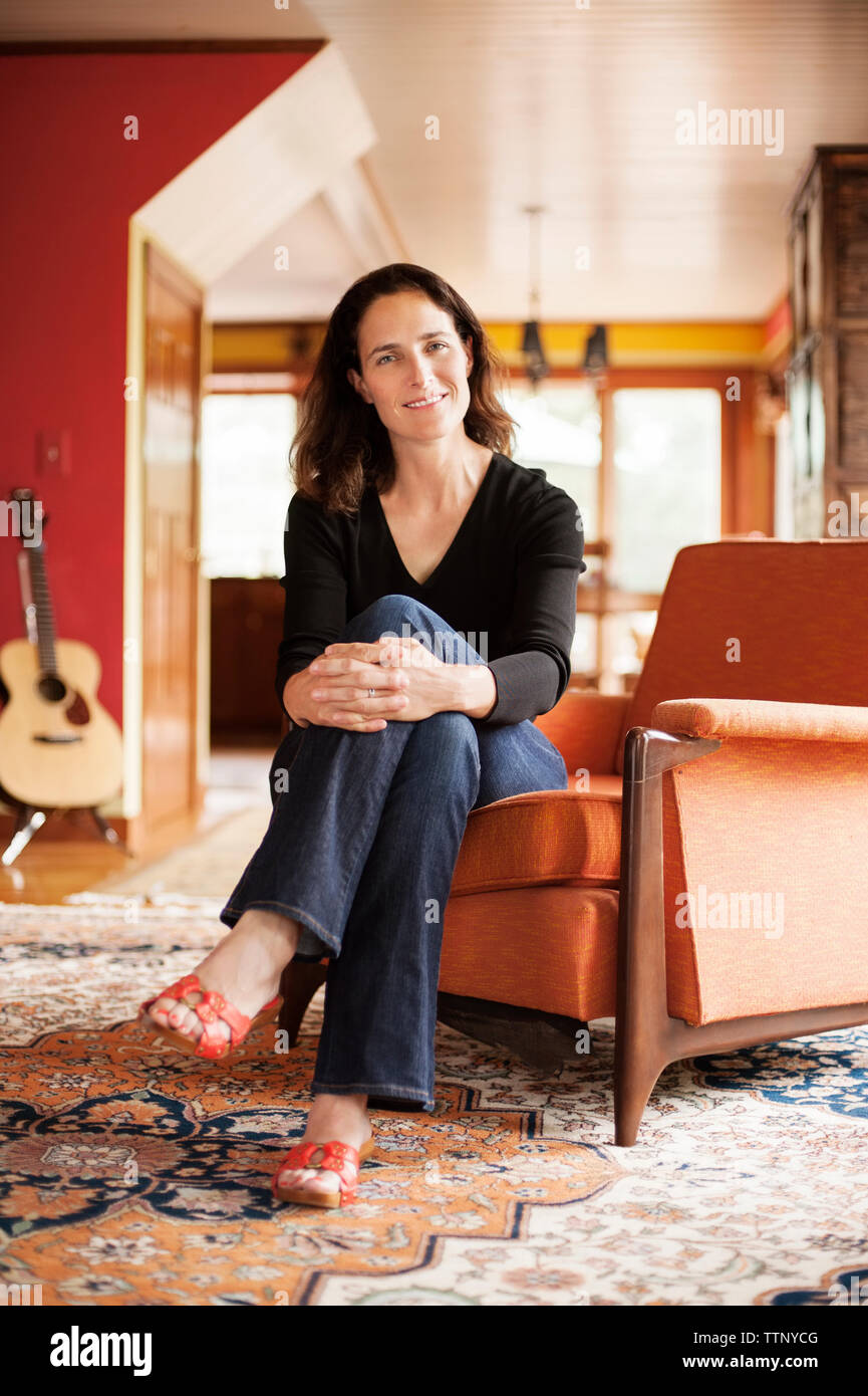 Portrait of smiling woman sitting on sofa at home Stock Photo - Alamy