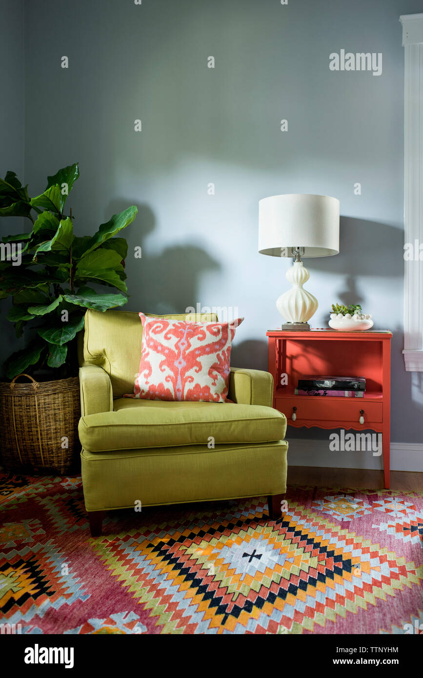 Cushion on armchair by houseplant and table at home Stock Photo