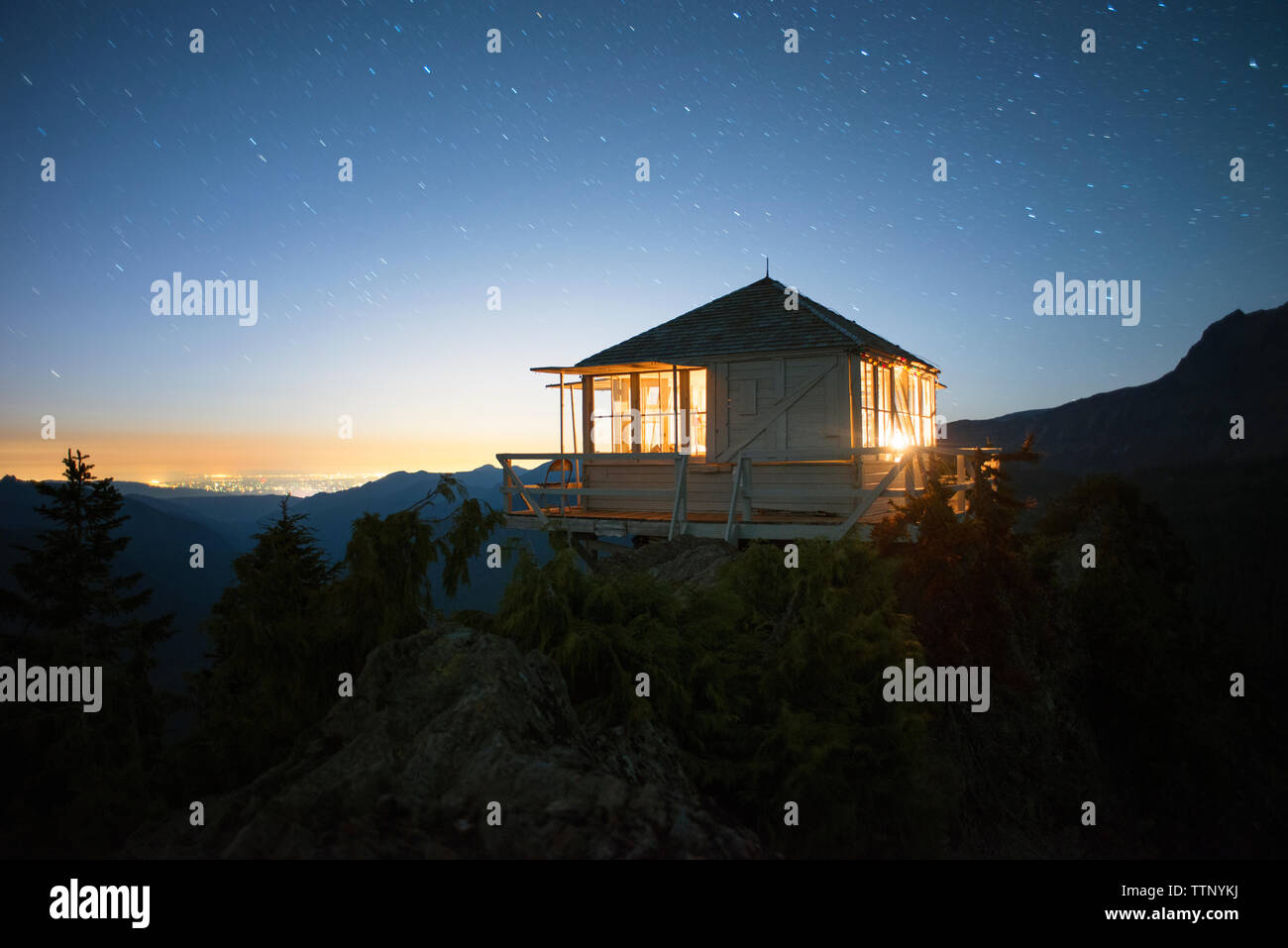 Illuminated cabin on cliff against sky at dusk Stock Photo