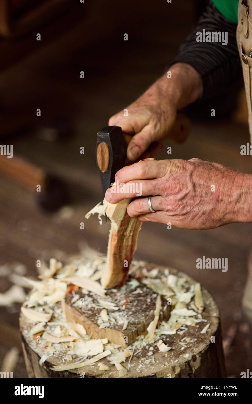 Cropped imager of carpenter shaping wood with chisel hammer at