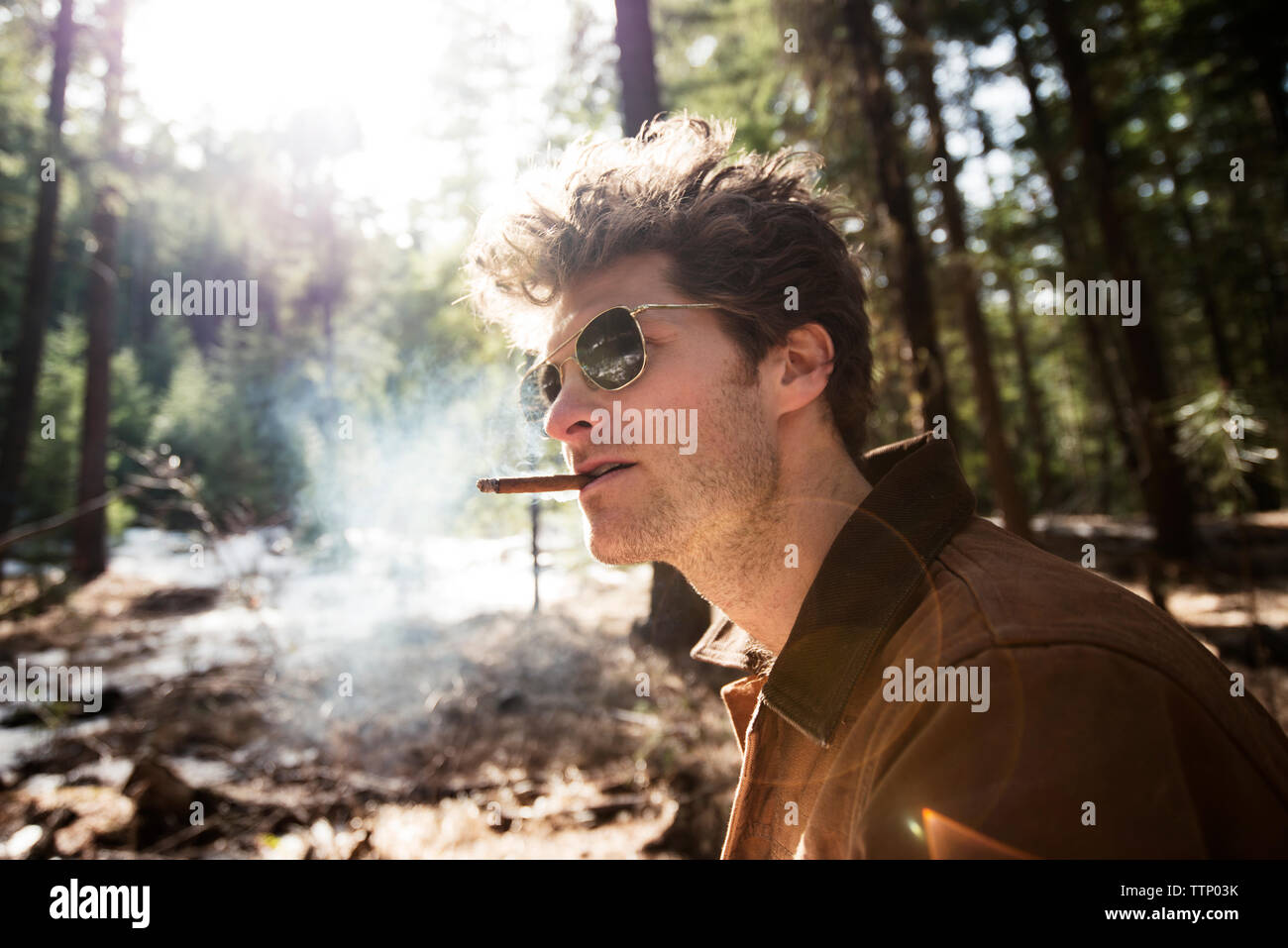Side view of man smoking cigar in forest Stock Photo