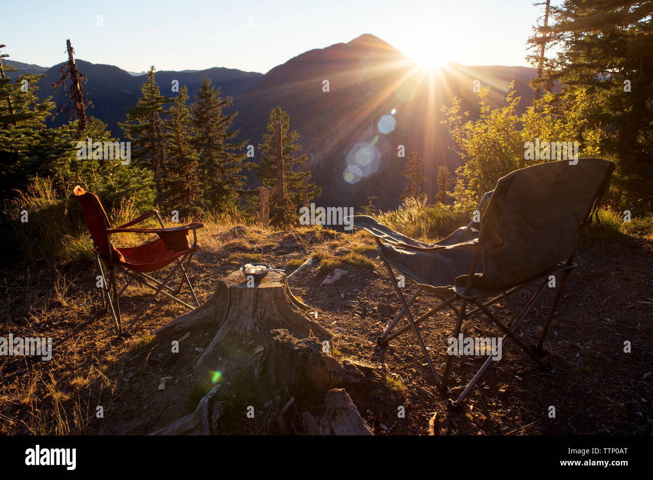 Folding chairs on field against mountain during sunset Stock Photo