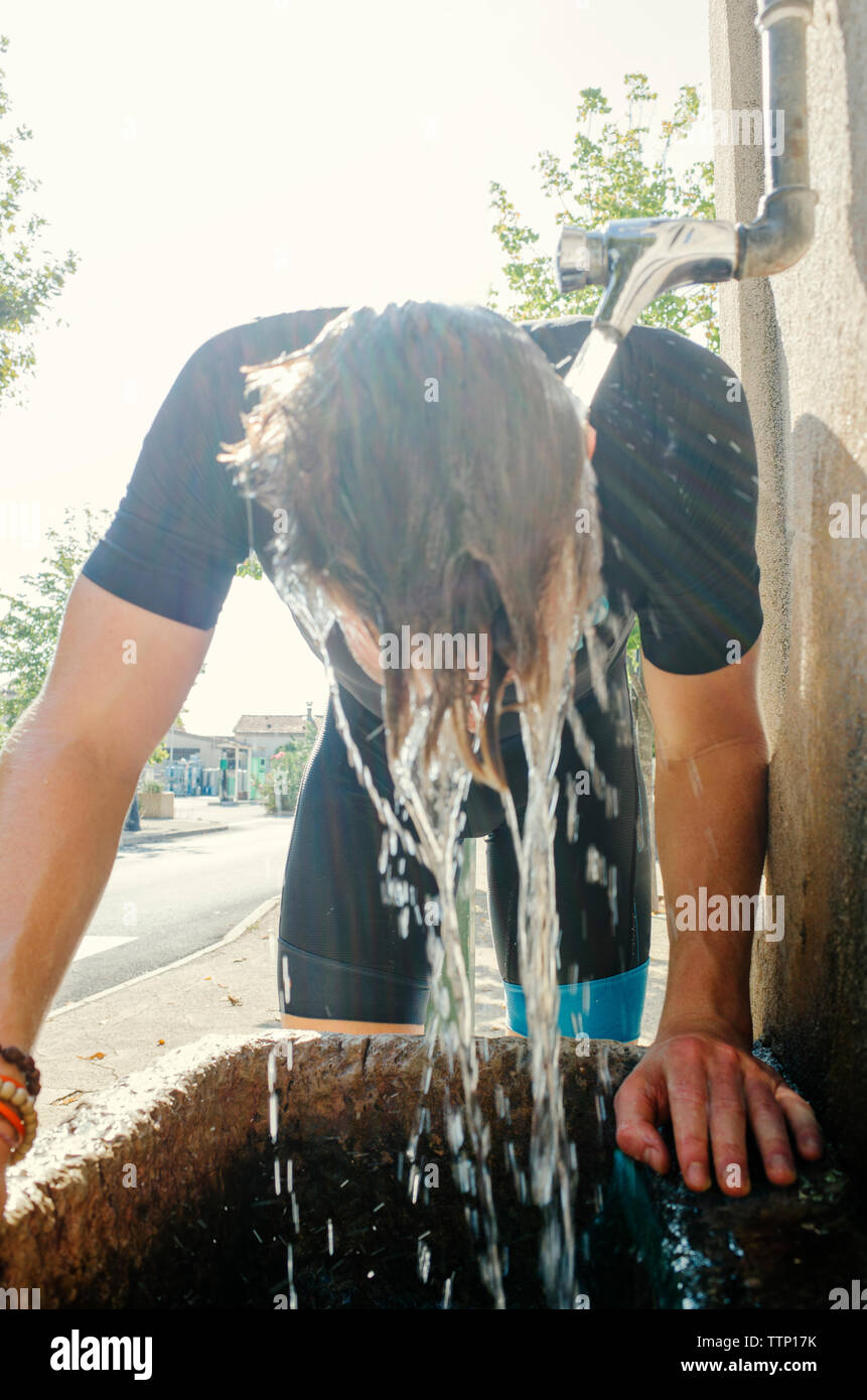 Man bending under faucet in running water Stock Photo