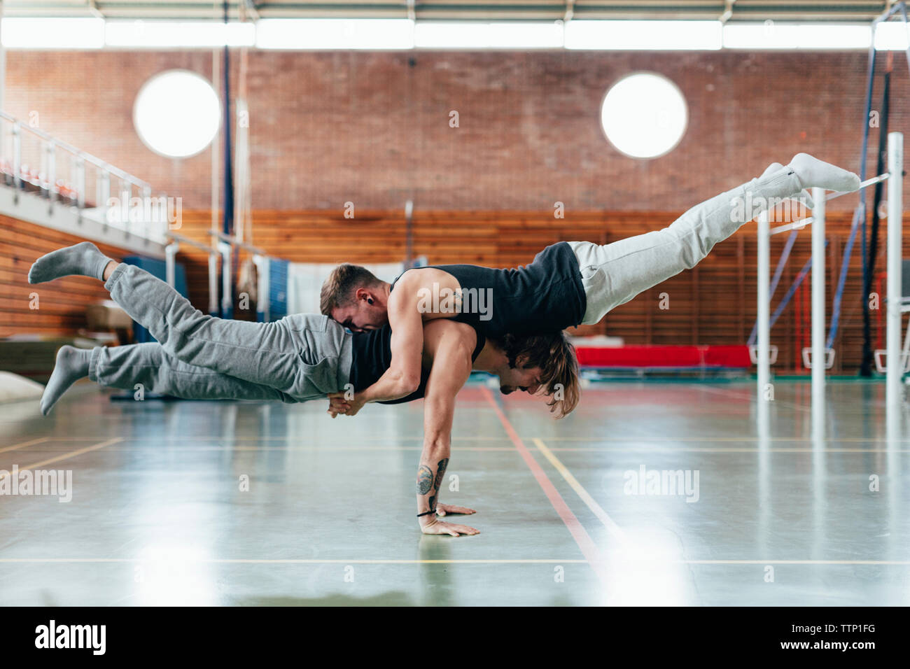 Full length side view of gymnasts practicing handstand at gym Stock Photo