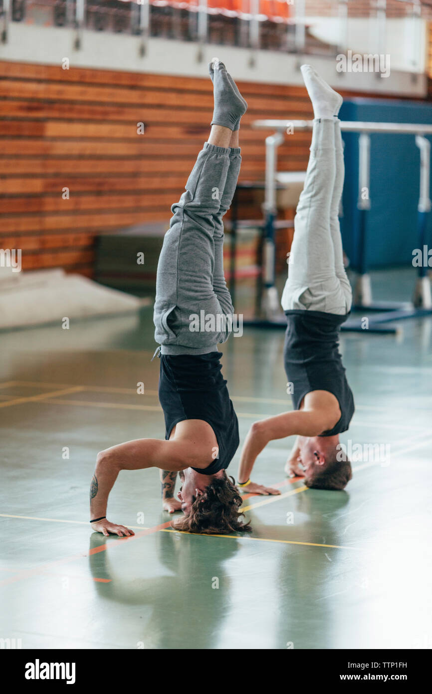 Full length of gymnasts practicing headstand at gym Stock Photo