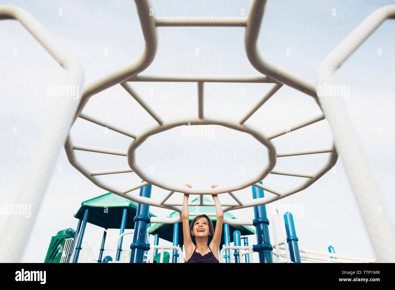 Playful girl hanging on jungle gym in playground Stock Photo Alamy