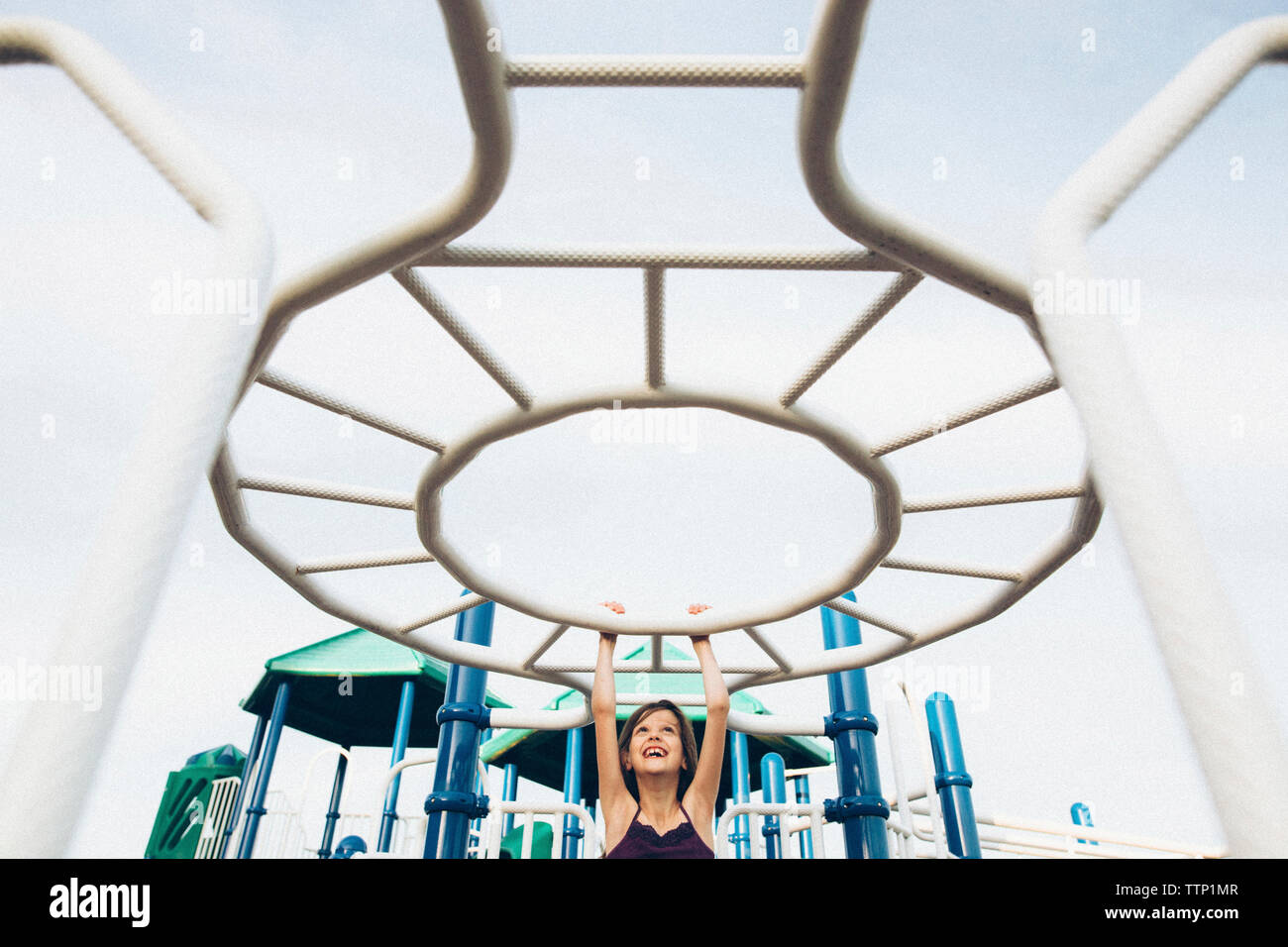 Playful girl hanging on jungle gym in playground Stock Photo