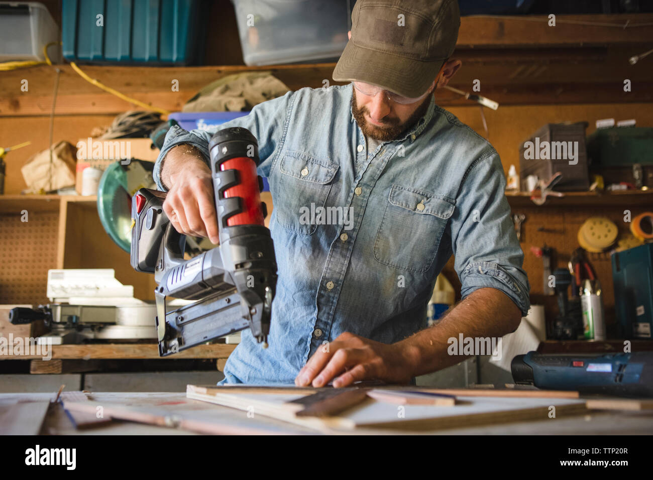 Artist using nail gun on wooden art at workshop Stock Photo