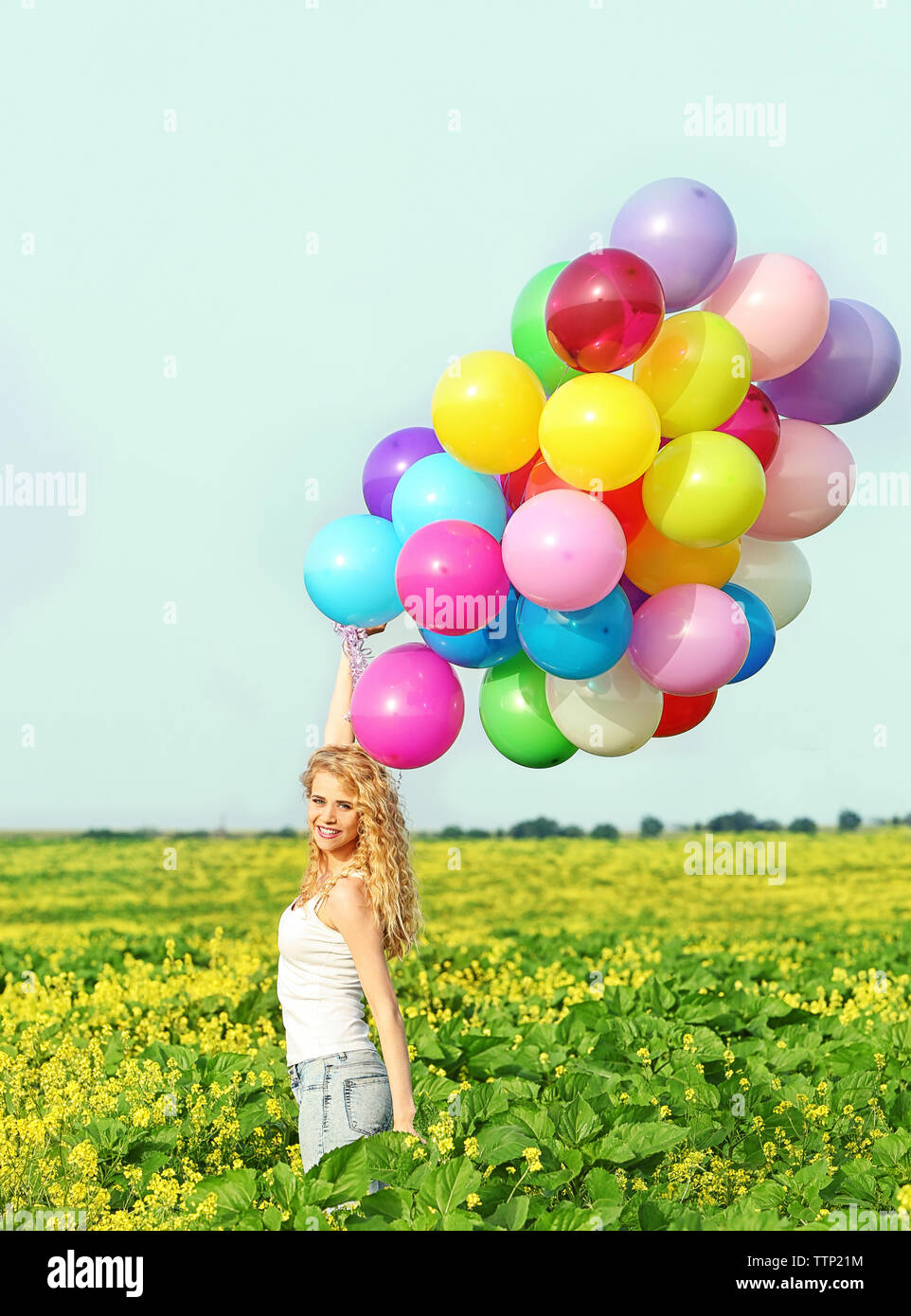 Happy Woman With Colorful Balloons In Field On Blue Sky Background happy-woman-with-colorful-balloons-in-field-on-blue-sky-background