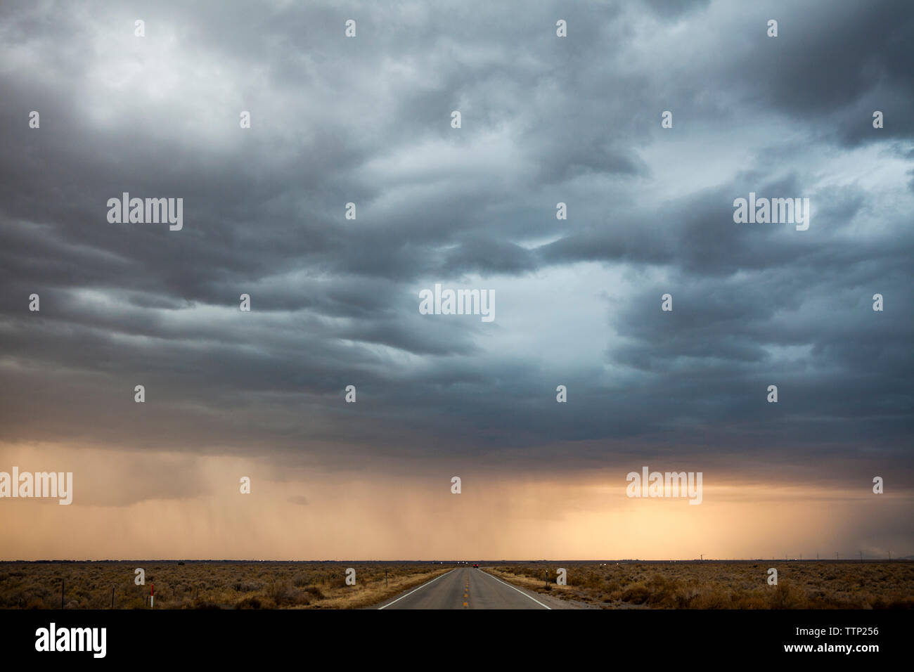 Idyllic view of stormy clouds raining over country road Stock Photo - Alamy