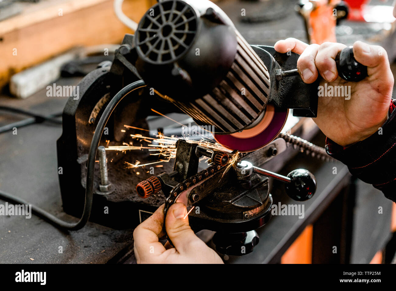 cropped hands of man welding chain in workshop Stock Photo