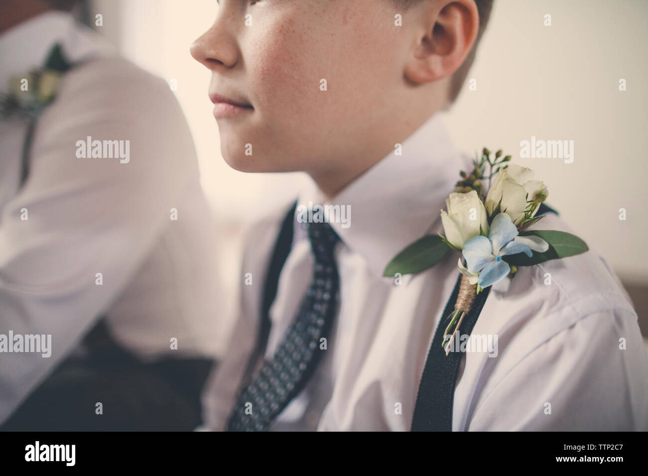 Close-up of pageboy with flowers on suspender sitting by bridegroom at home Stock Photo