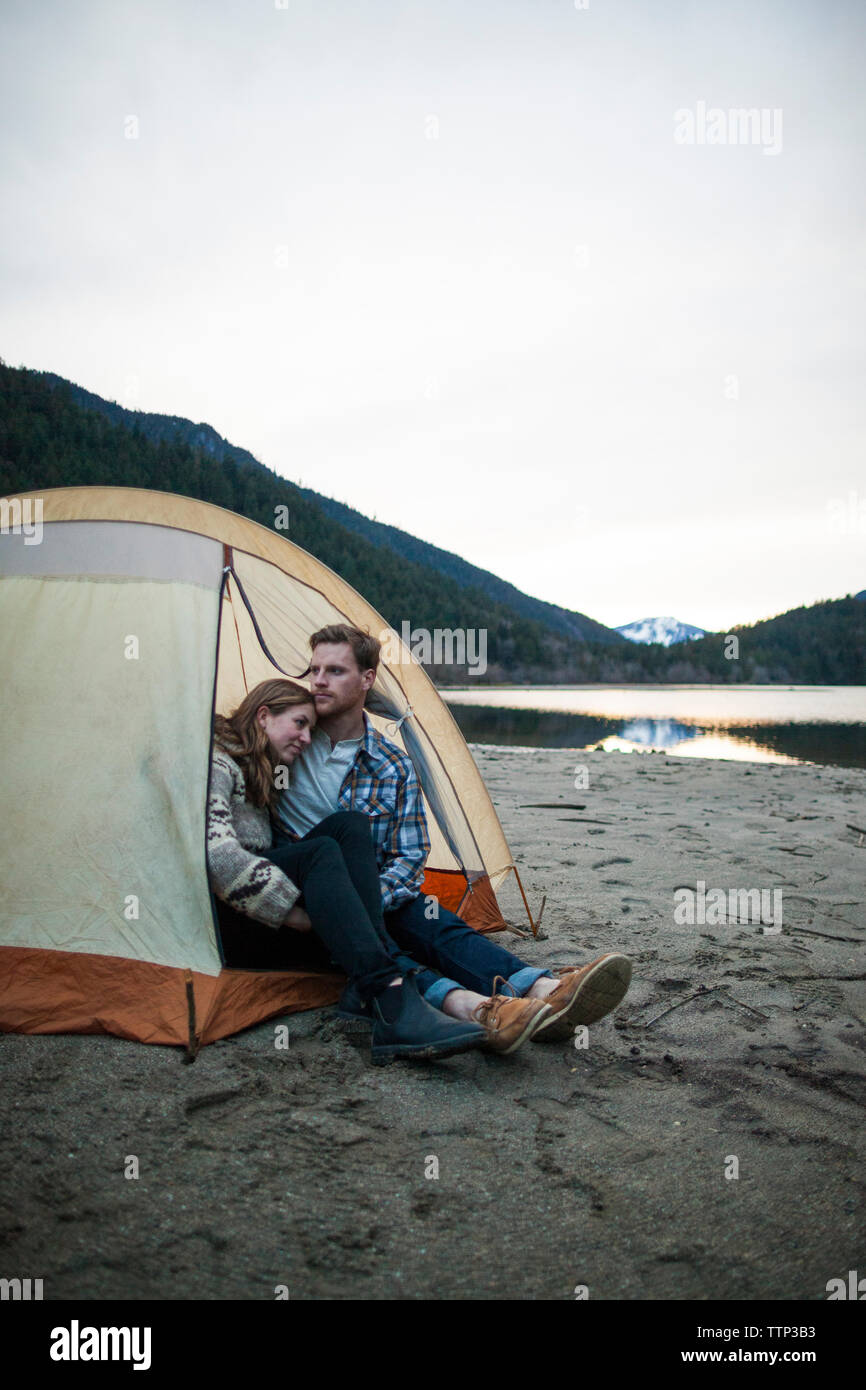 Young couple sitting in tent on lakeshore at Silver Lake Provincial Park Stock Photo