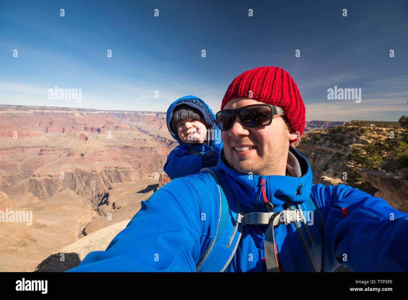 Portrait of happy father with cute son standing at Grand Canyon National Park against sky during sunny day Stock Photo