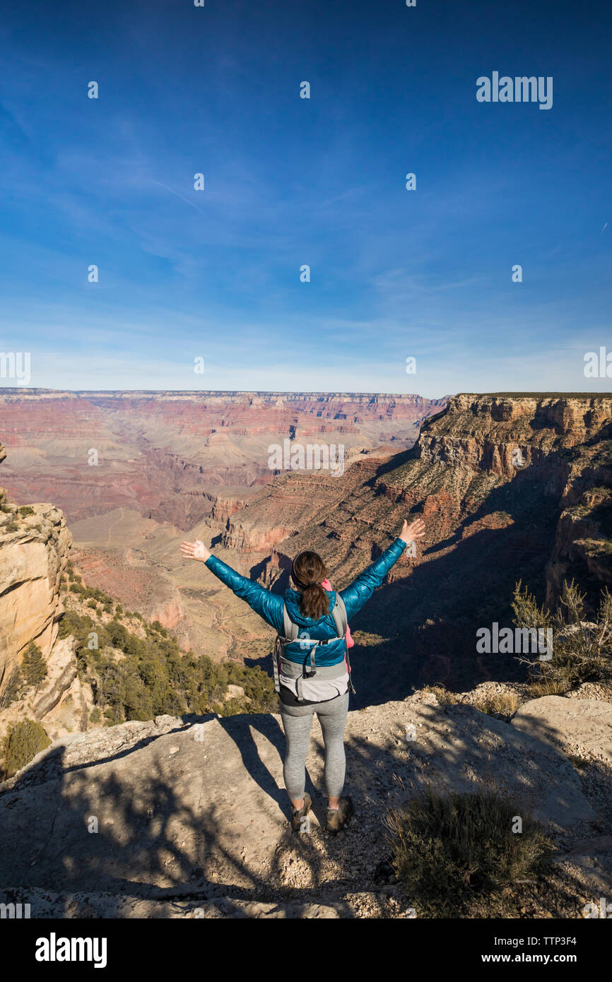 Rear view of female hiker with arms raised standing at Grand Canyon ...