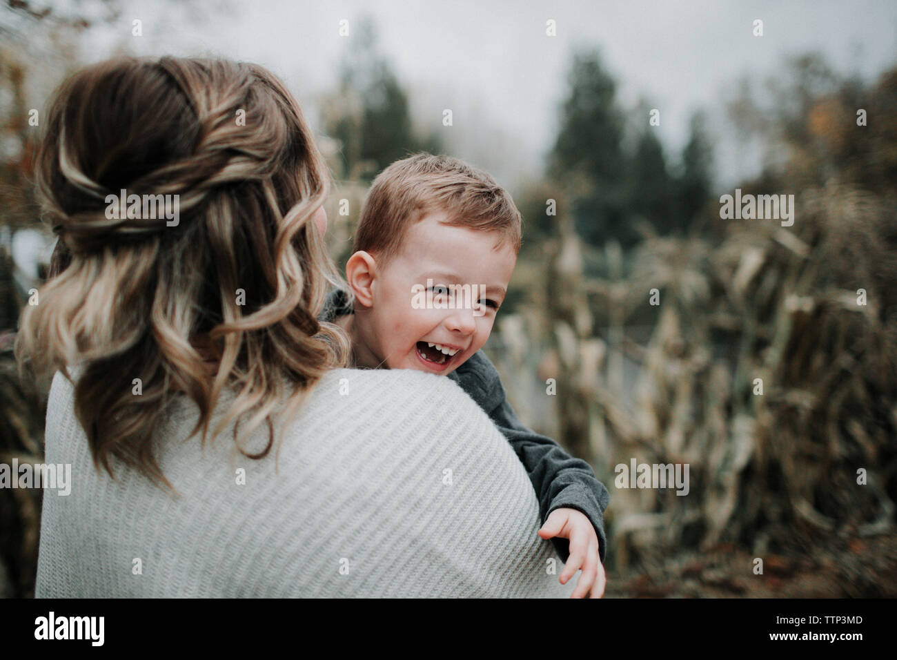 Mother carrying cute cheerful son on field Stock Photo