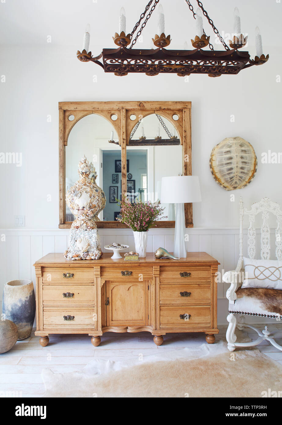 Chandelier Over Cabinet And Mirrors In Beach Cottage Stock Photo