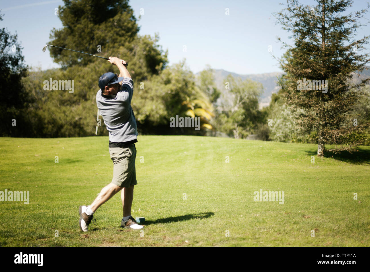 Man swinging golf club on golf course Stock Photo