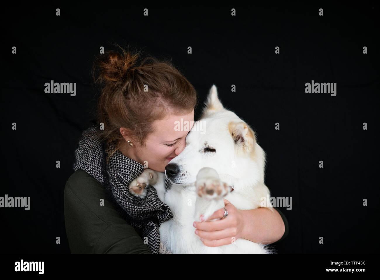 Happy woman holding dog against black background Stock Photo