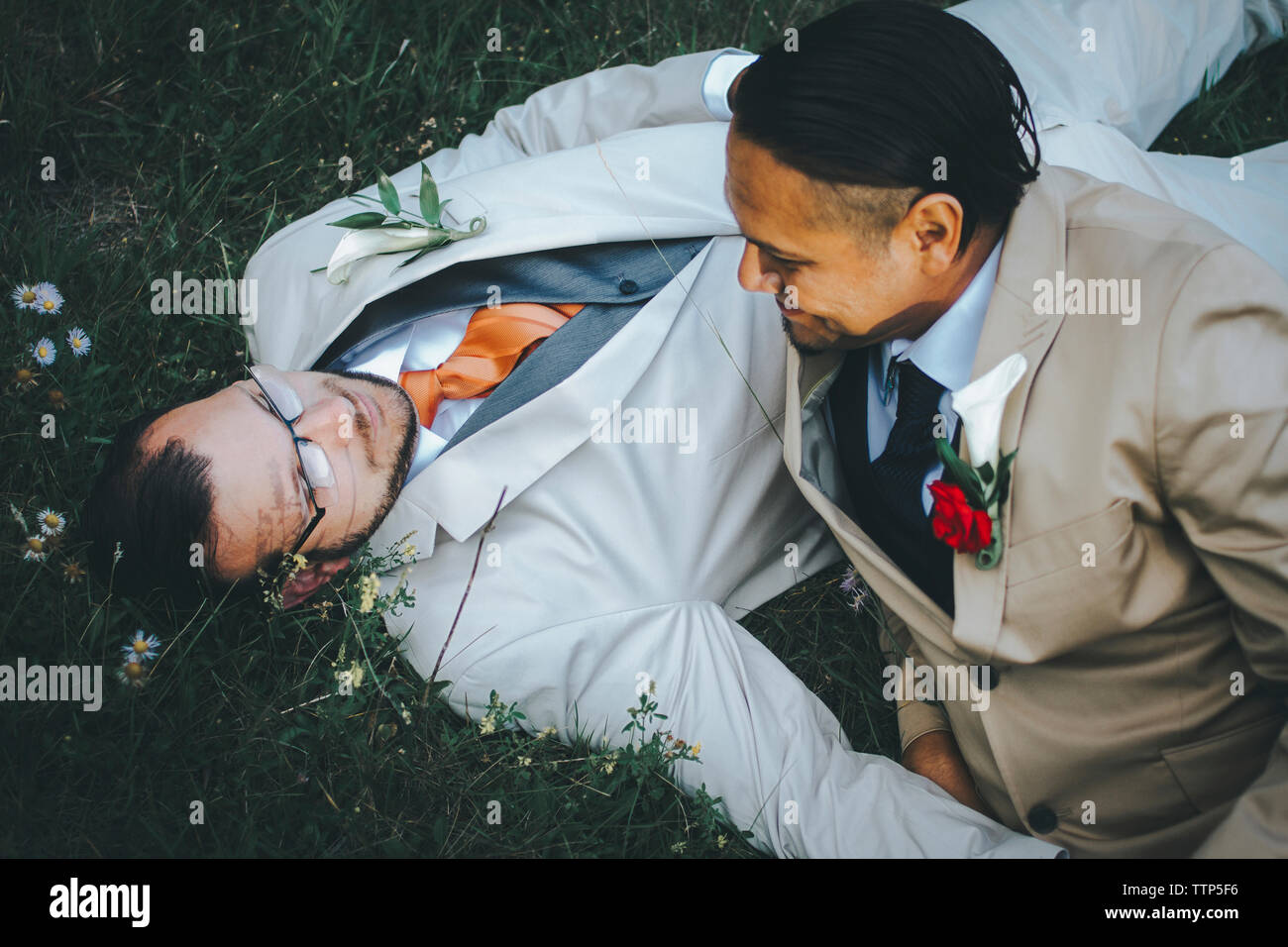Happy homosexual couple relaxing on grassy field Stock Photo