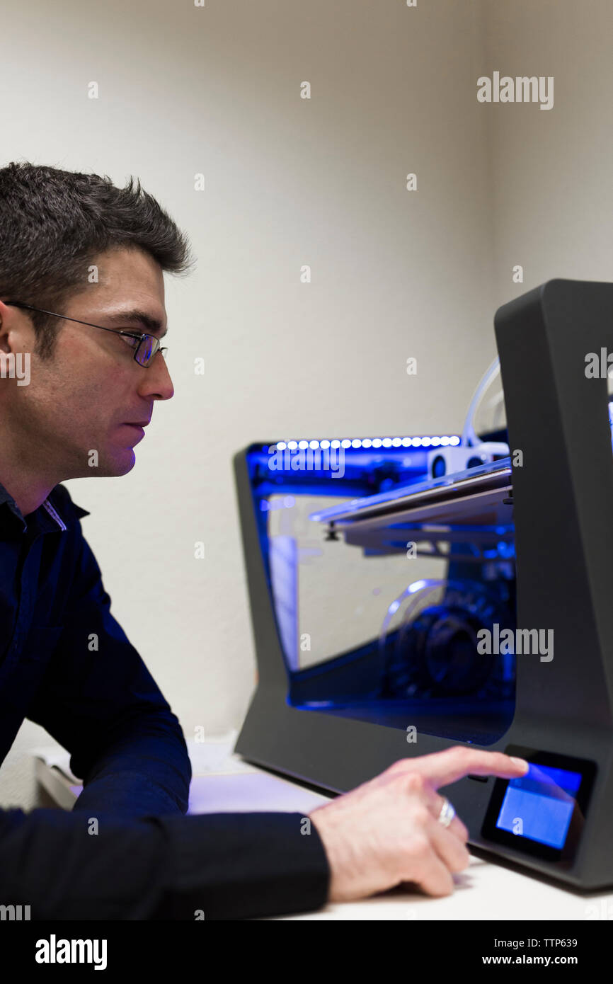 Engineer operating 3D printer on table in office Stock Photo