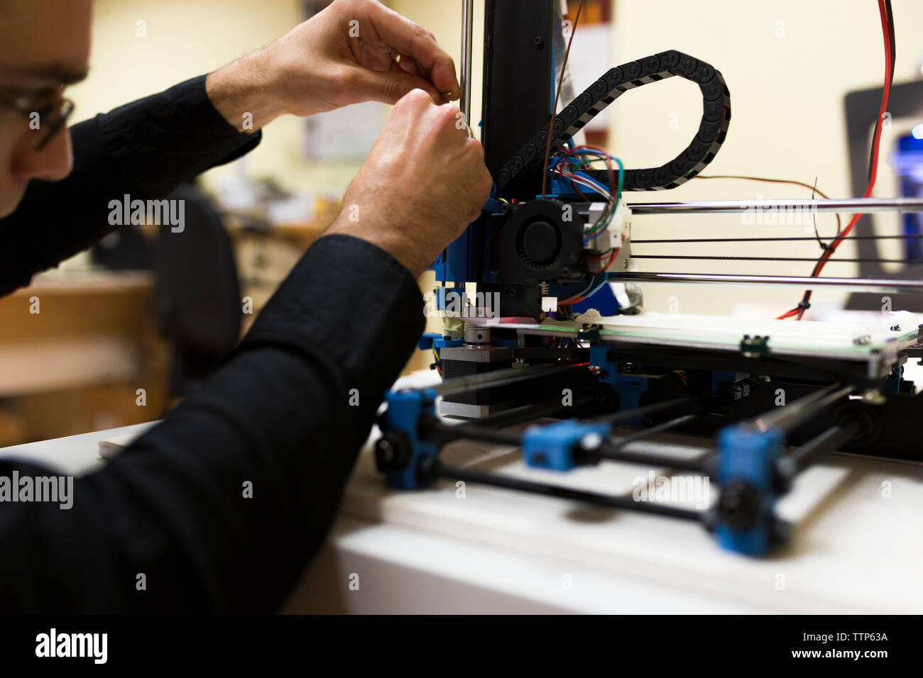 Male engineer fixing 3D printer on table Stock Photo