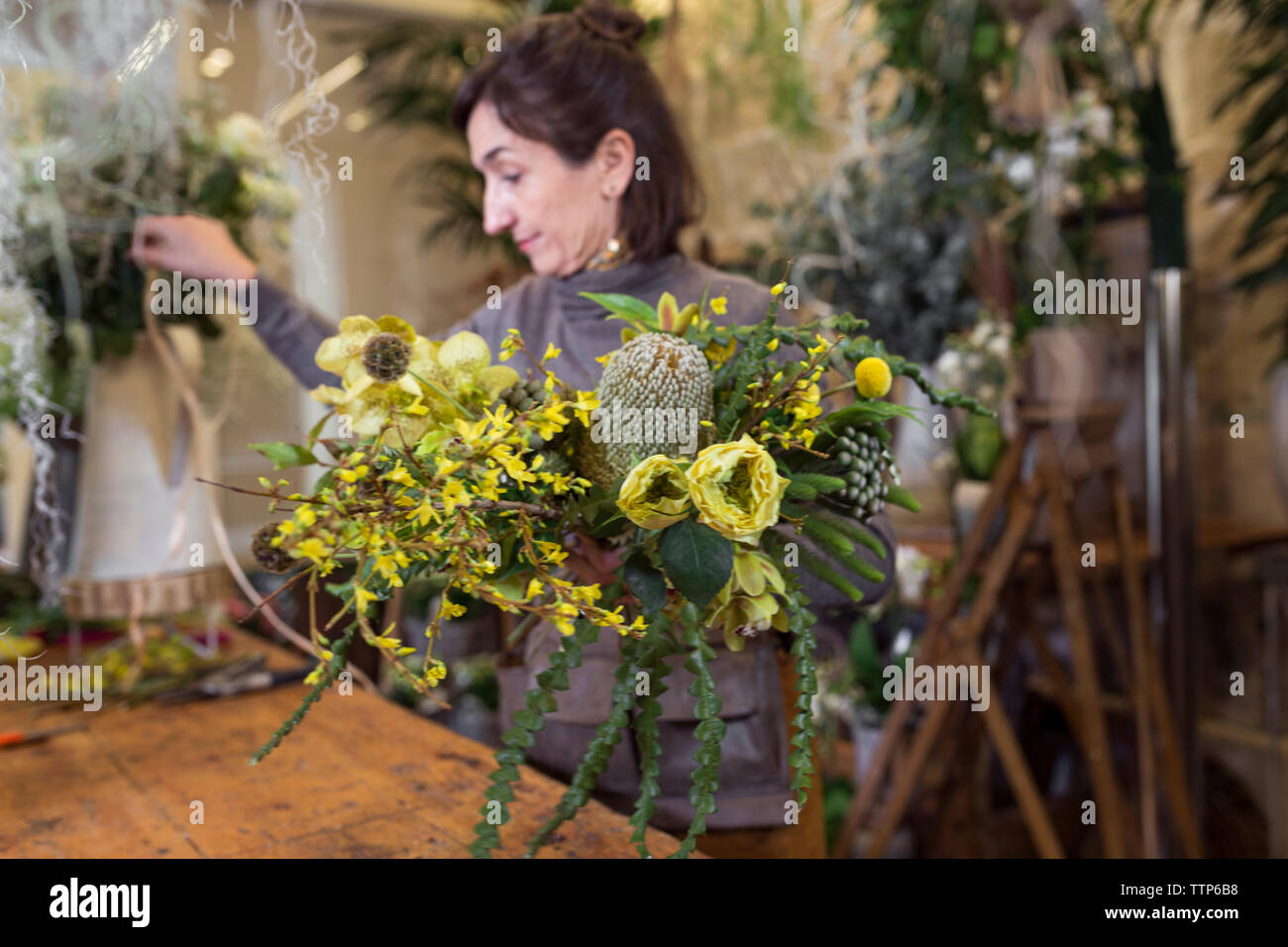 Senior woman arranging flowers at flower shop desk Stock Photo