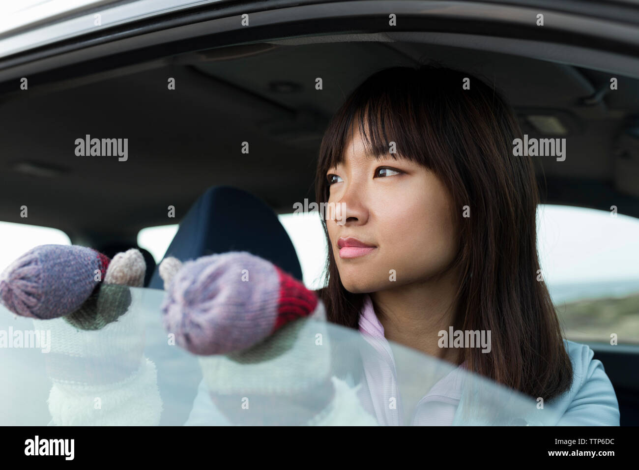 Young Chinese woman sitting in a car looking out the car window Stock Photo