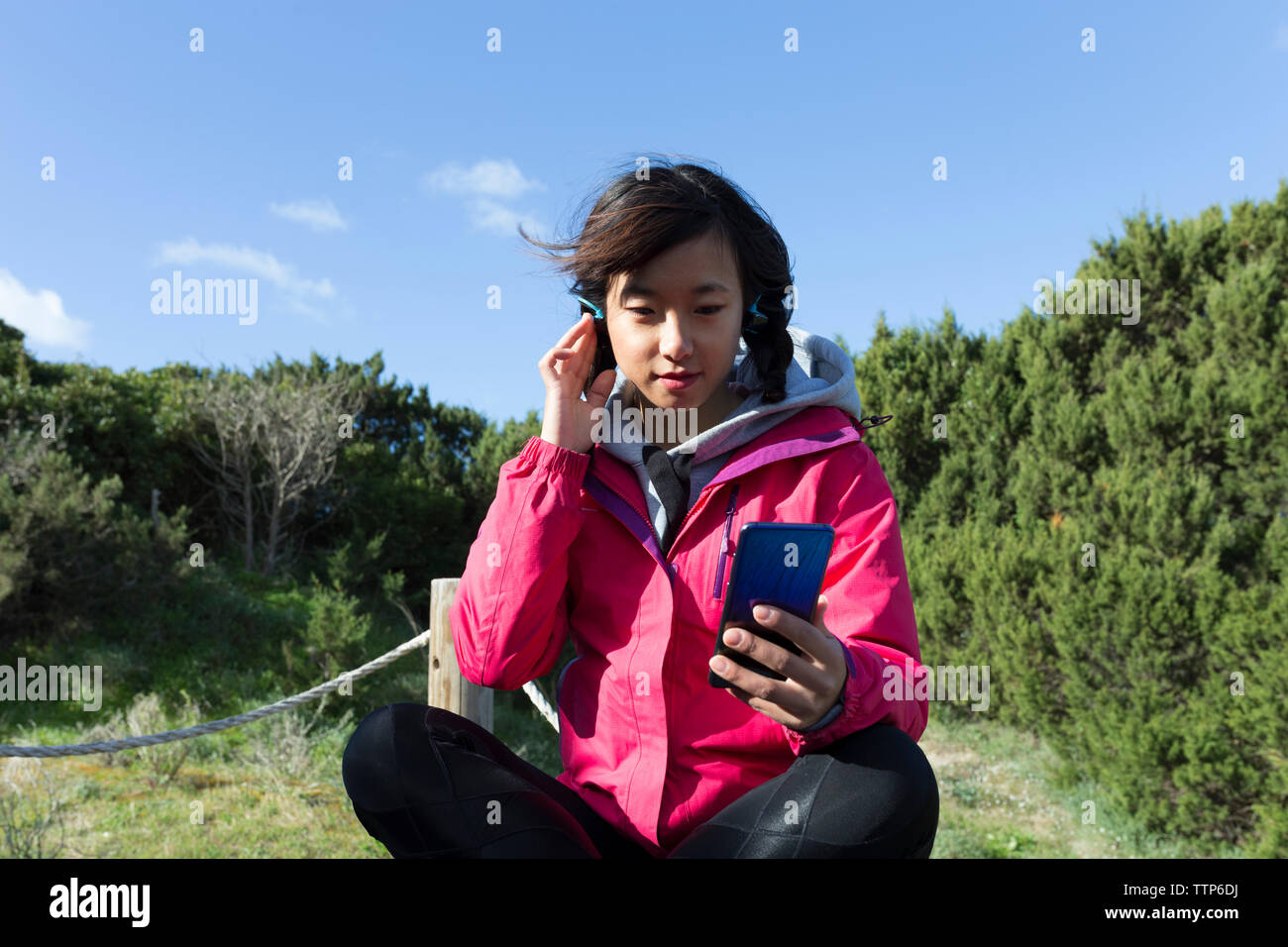 Young Chinese woman in the nature using smartphone and listening music Stock Photo