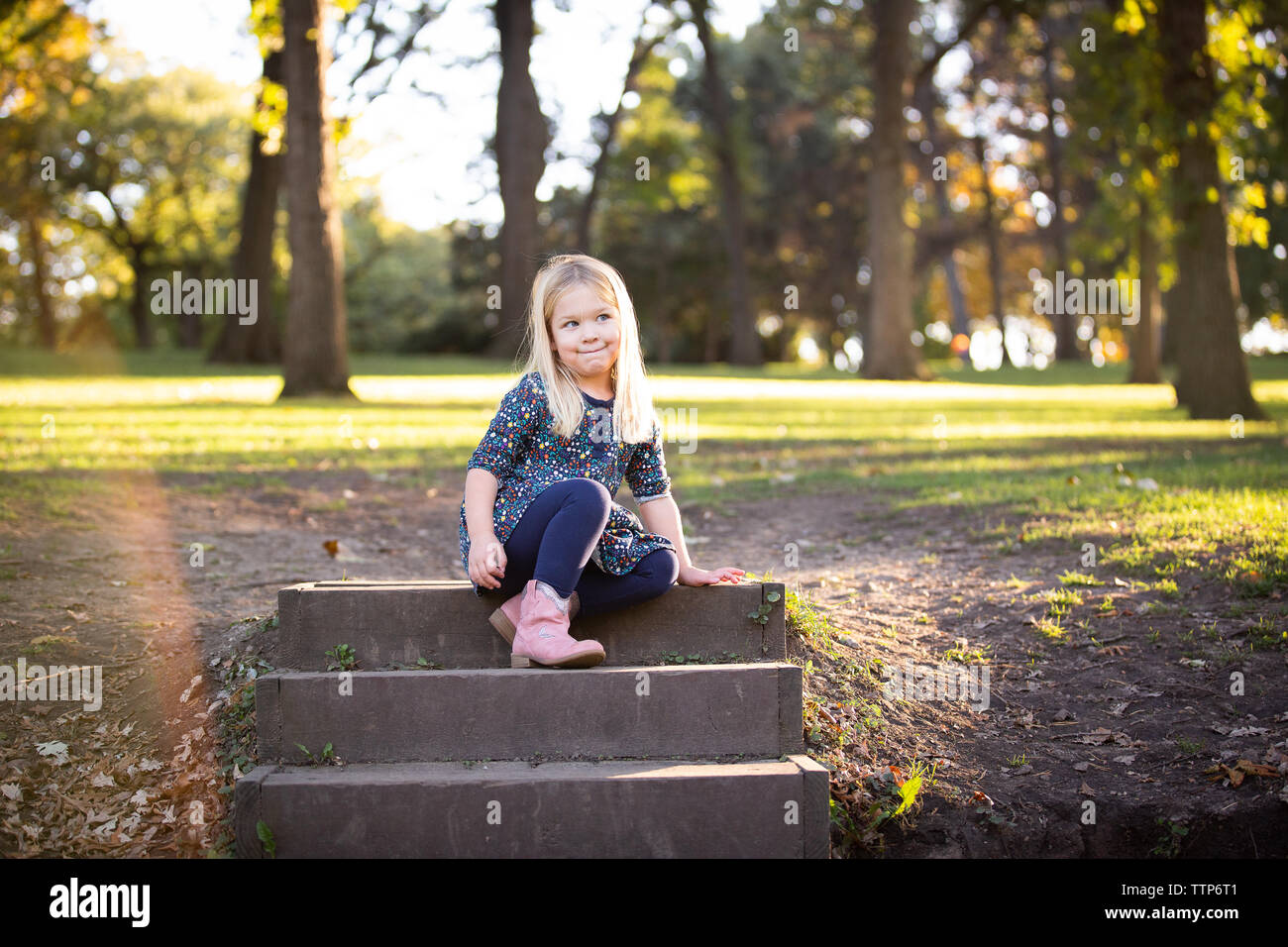 cute blonde girl sitting on steps outdoors thinking Stock Photo