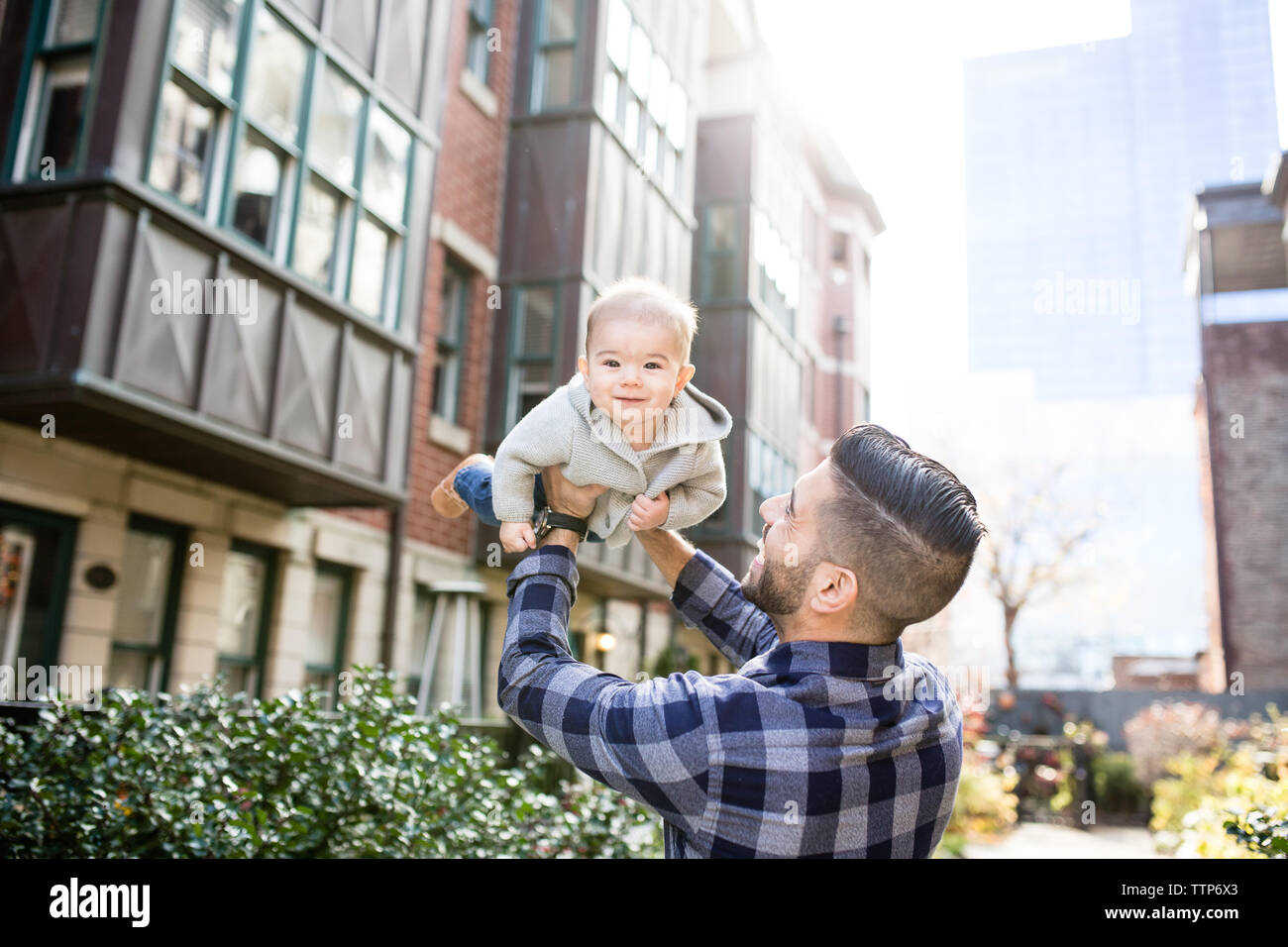 Smiling dad and baby outdoors in city holding baby up Stock Photo