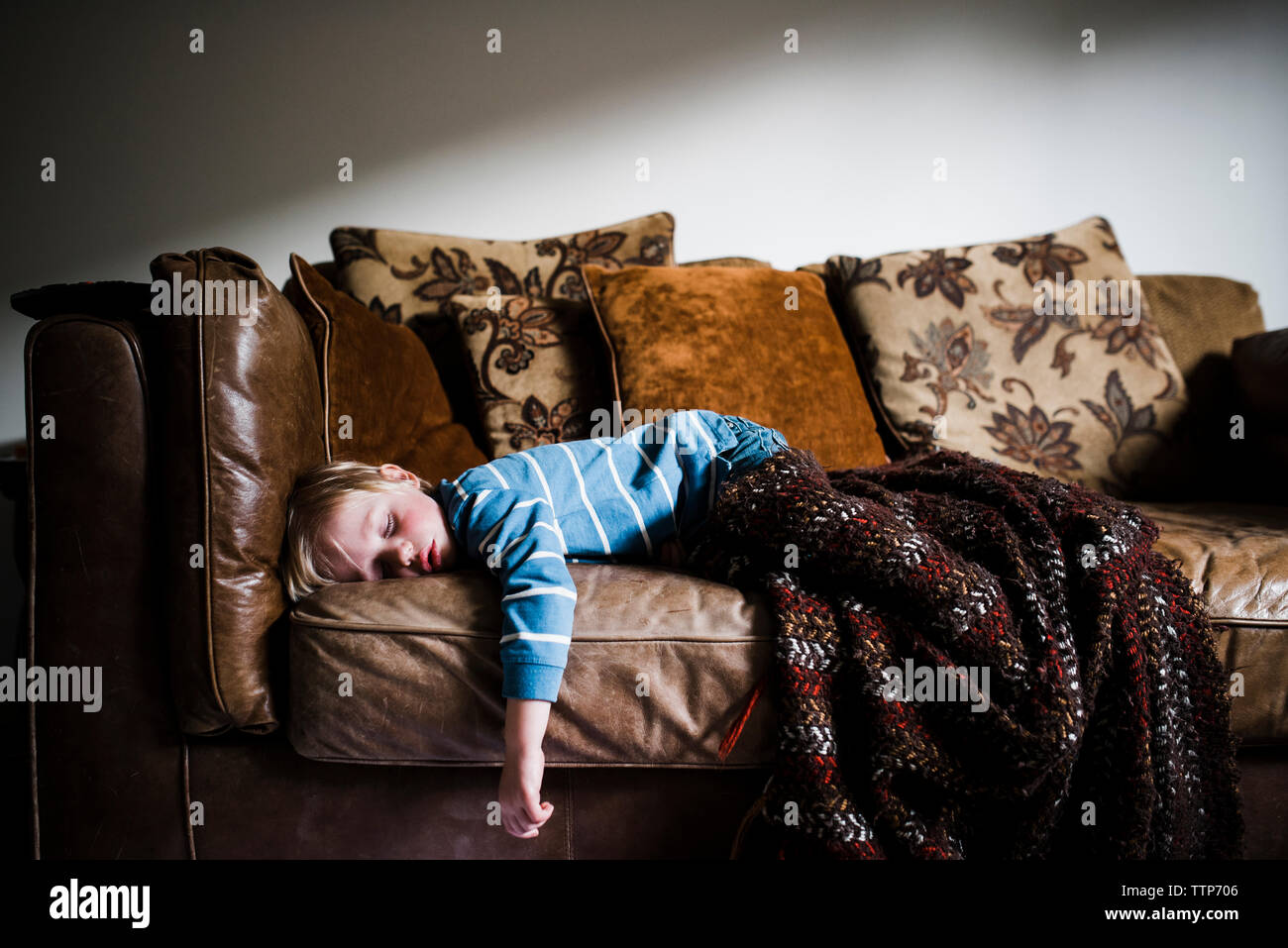 Boy sleeping on couch at home against wall Stock Photo Alamy