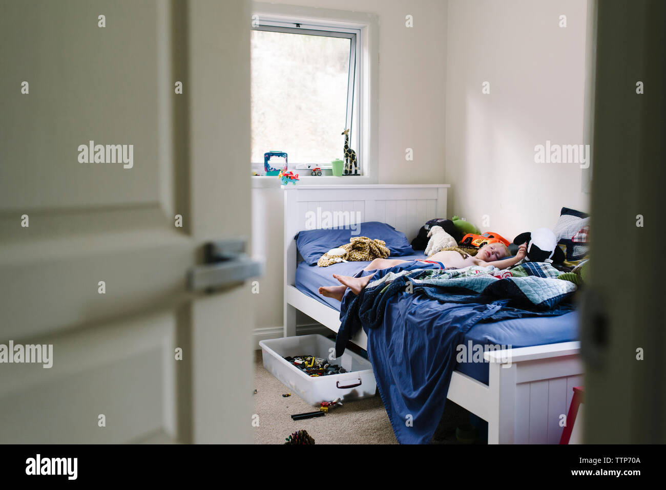 Boy sleeping on bed at home seen through doorway Stock Photo Alamy