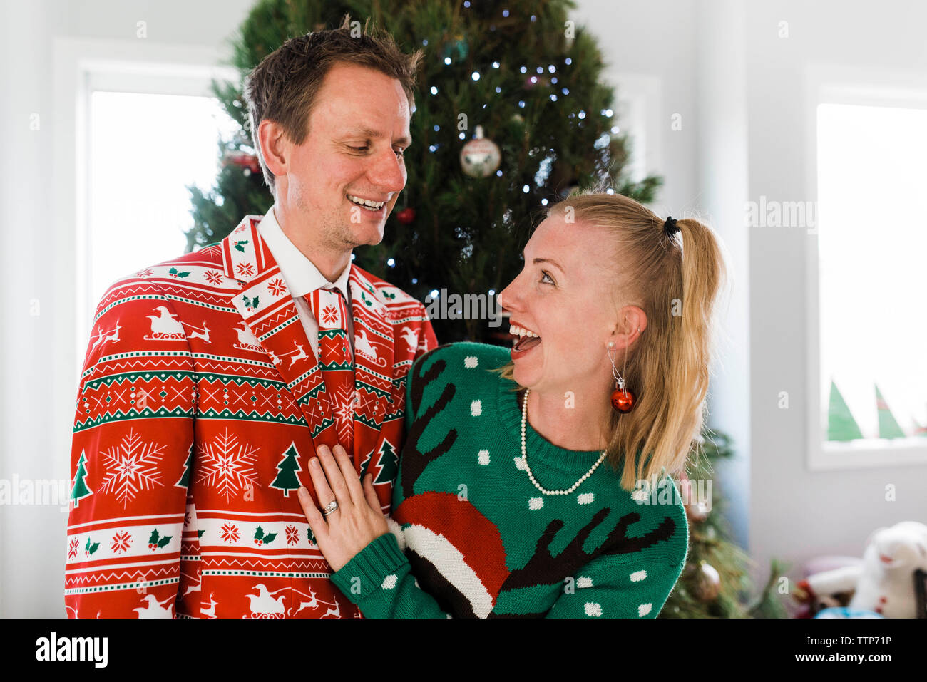 Cheerful couple standing against christmas Tree at home Stock Photo