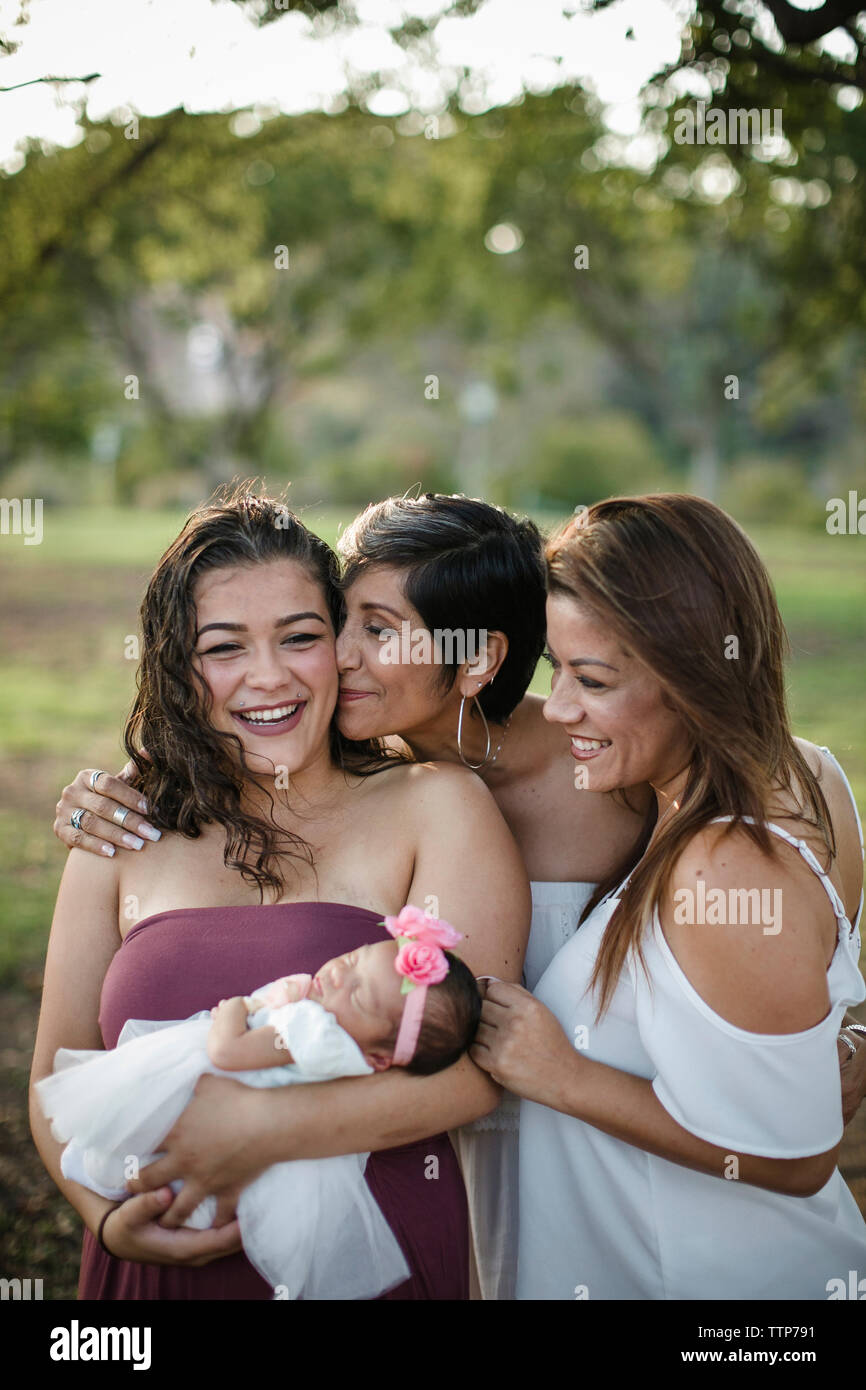 Happy family with newborn baby girl standing on field at park Stock Photo