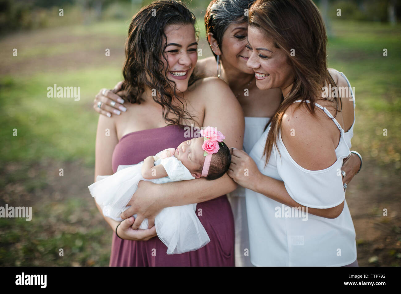 Happy family with newborn baby girl standing at park Stock Photo