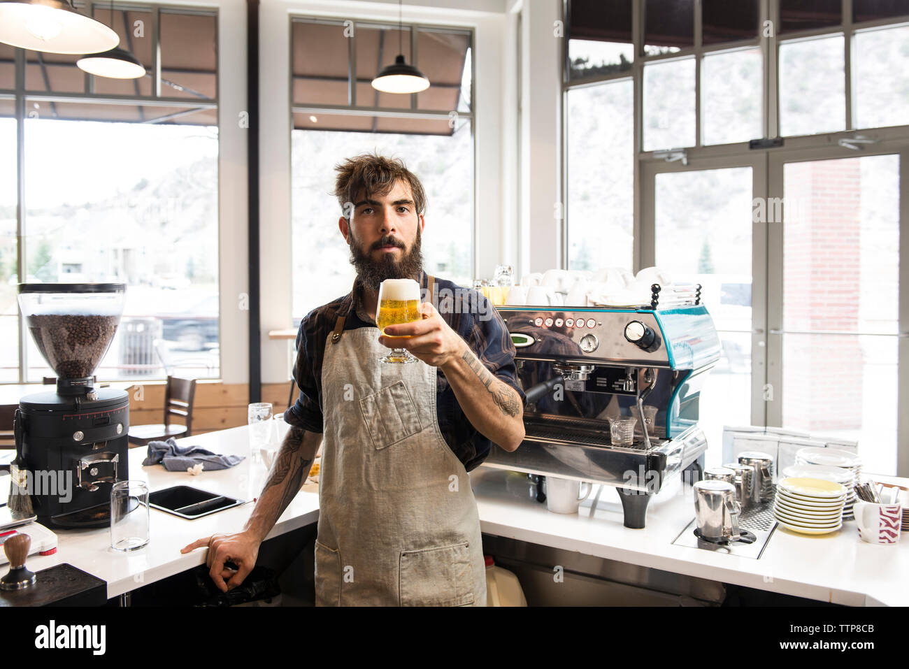 Portrait of man holding beer in coffee shop Stock Photo