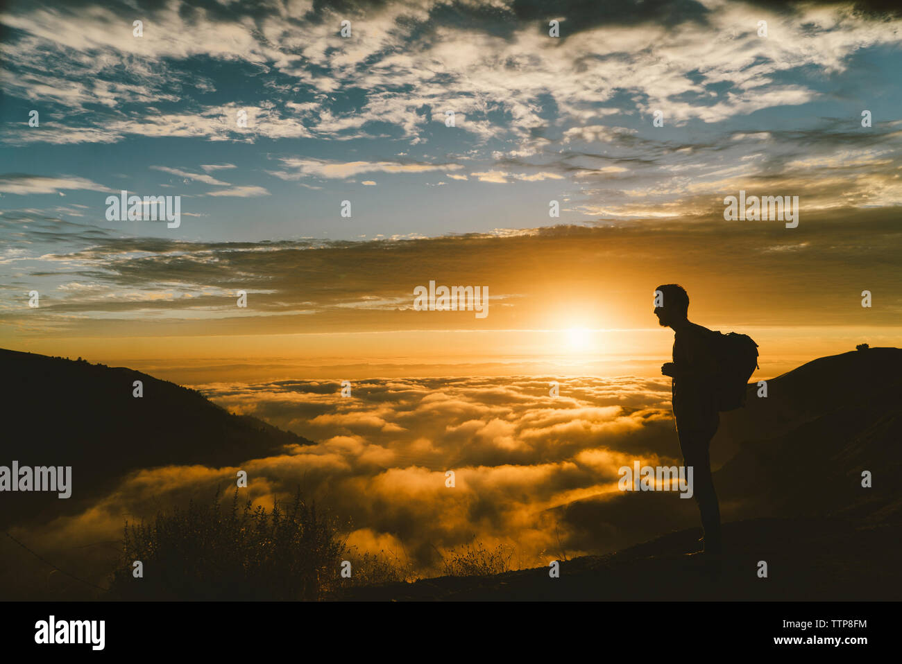 Silhouette male hiker standing on mountain during sunset Stock Photo