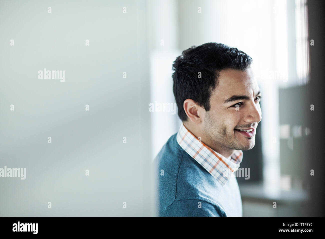 Happy businessman leaning against wall in office Stock Photo - Alamy
