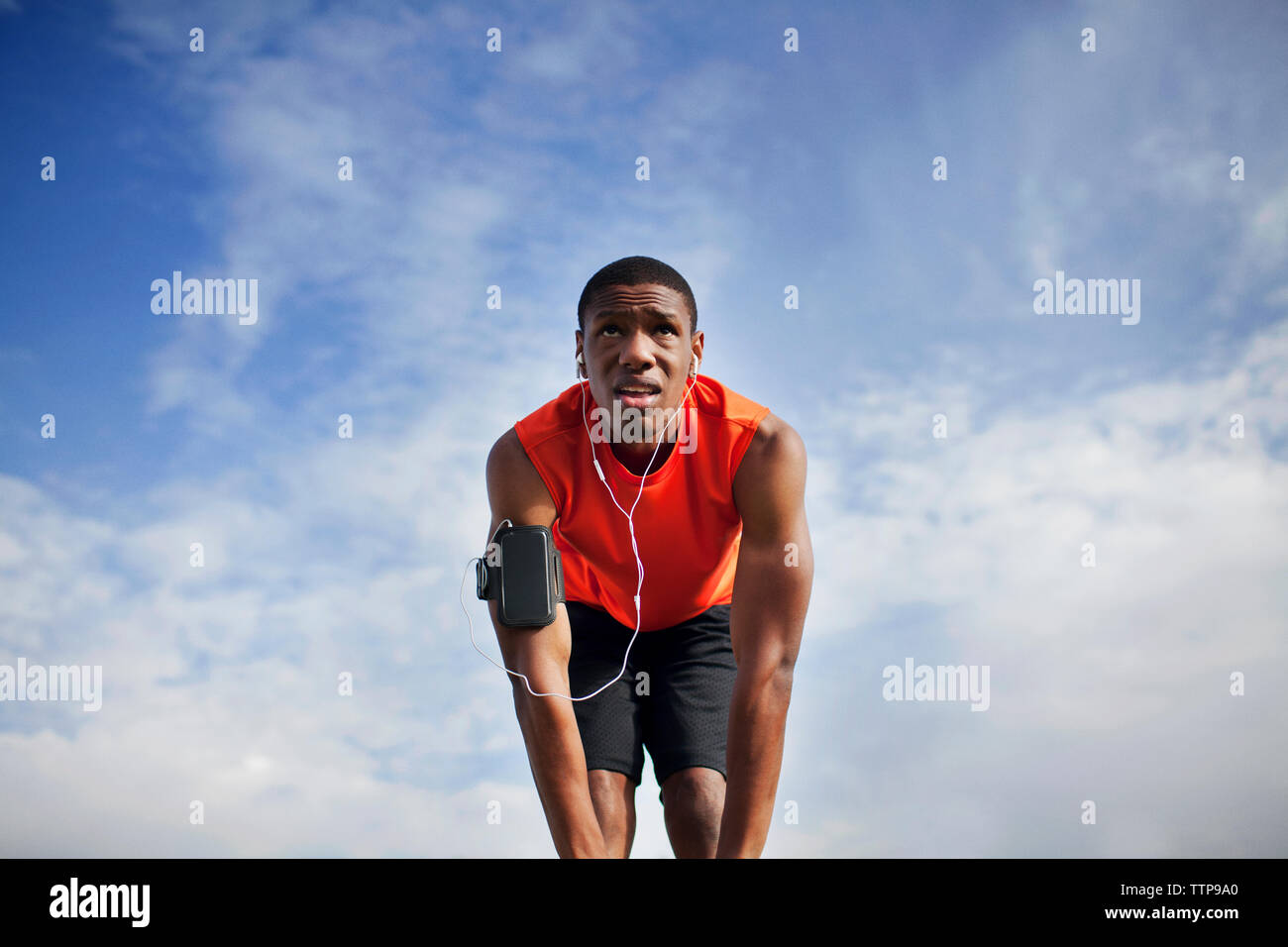 Low angle view of man exercising against cloudy sky on sunny day Stock Photo