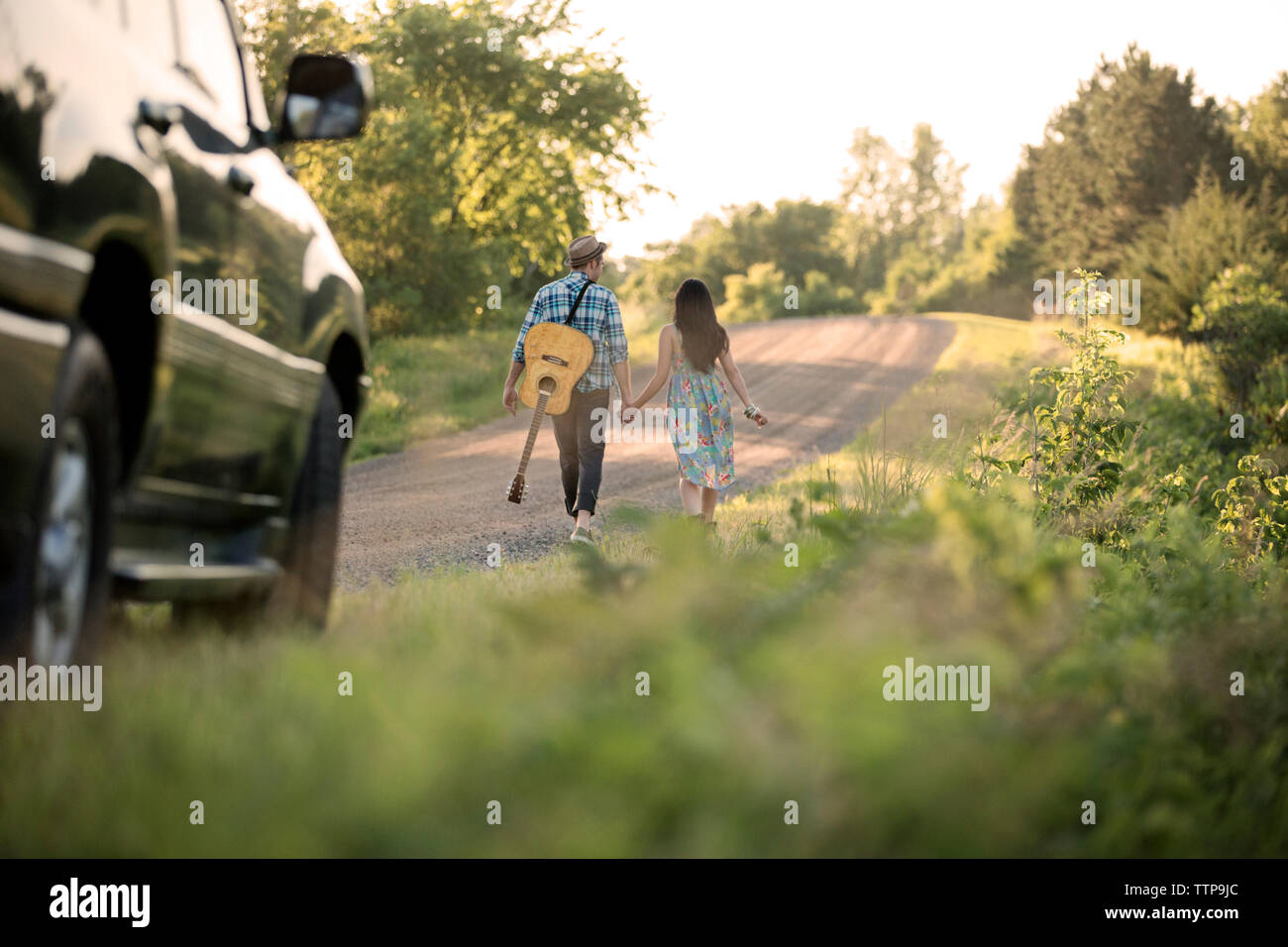 Rear view of couple holding hands and walking on road Stock Photo - Alamy