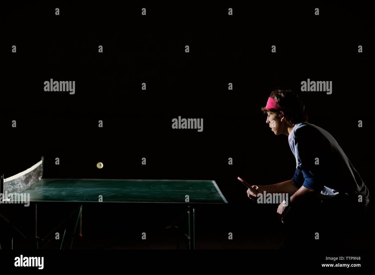 Man playing table tennis against black background Stock Photo