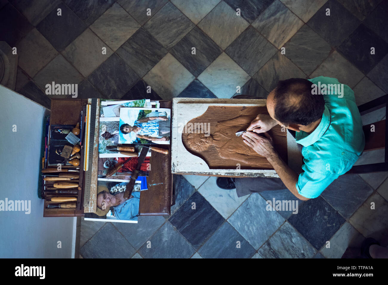 Overhead view of man carving while sitting in workshop Stock Photo