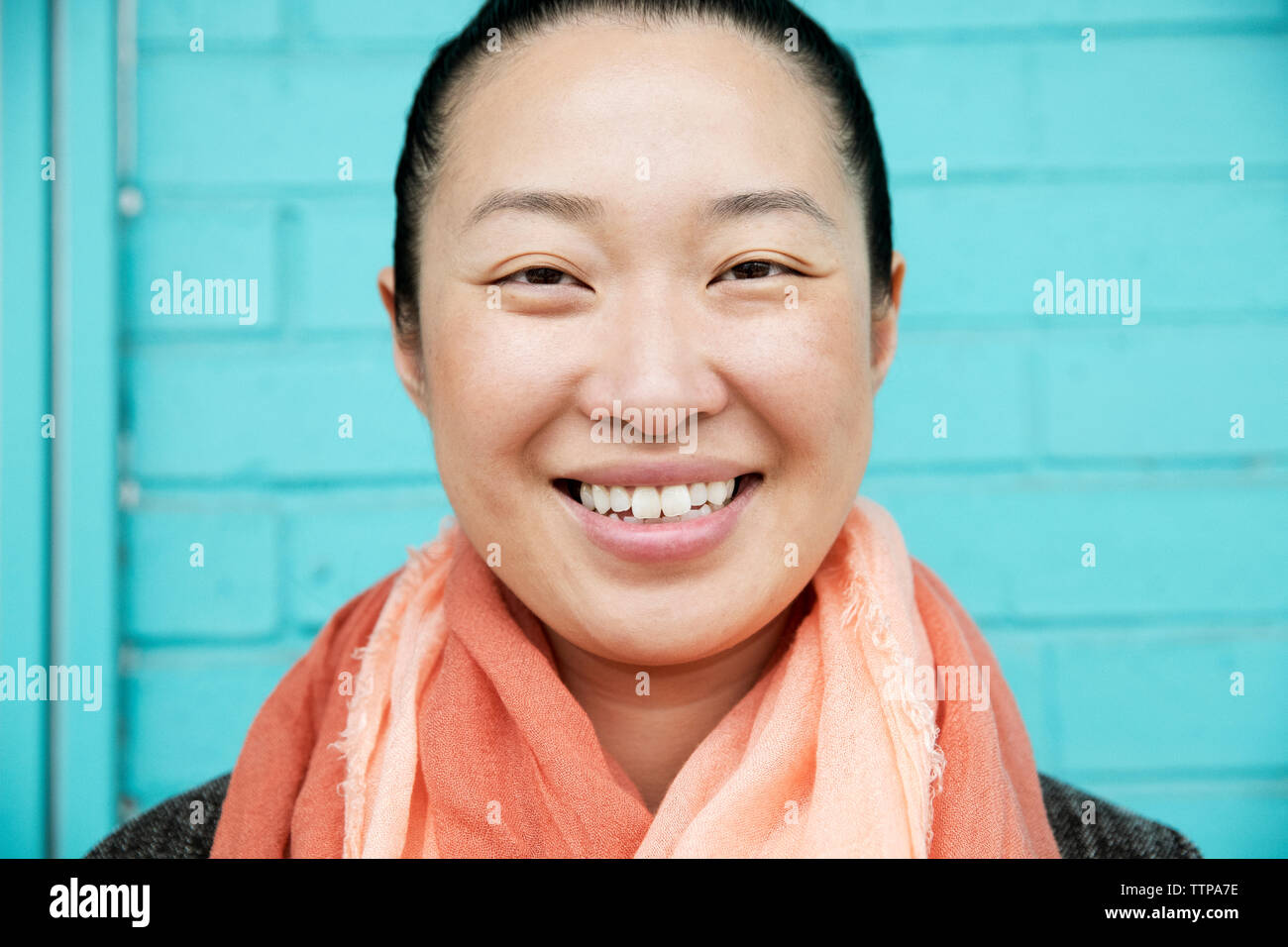 Close-up portrait of happy woman against blue wall Stock Photo