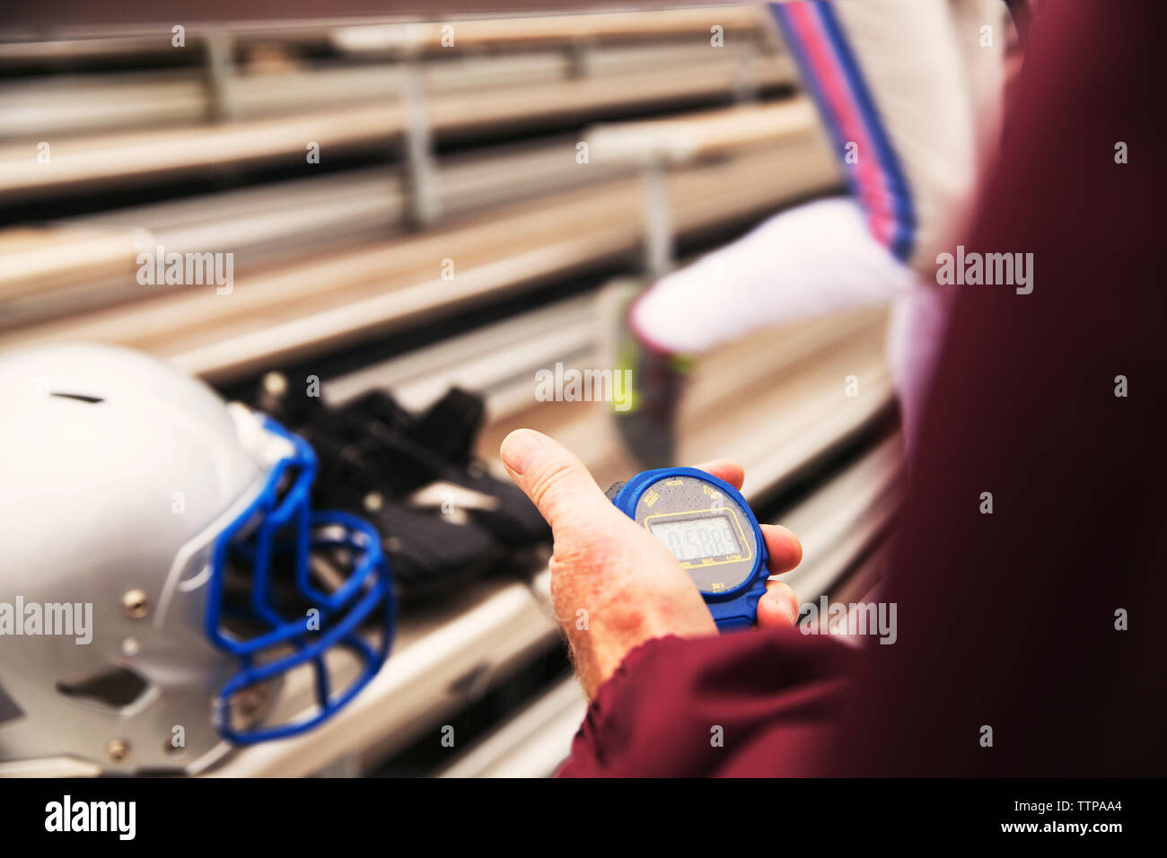 Cropped hand of American football coach holding stopwatch at stadium Stock Photo