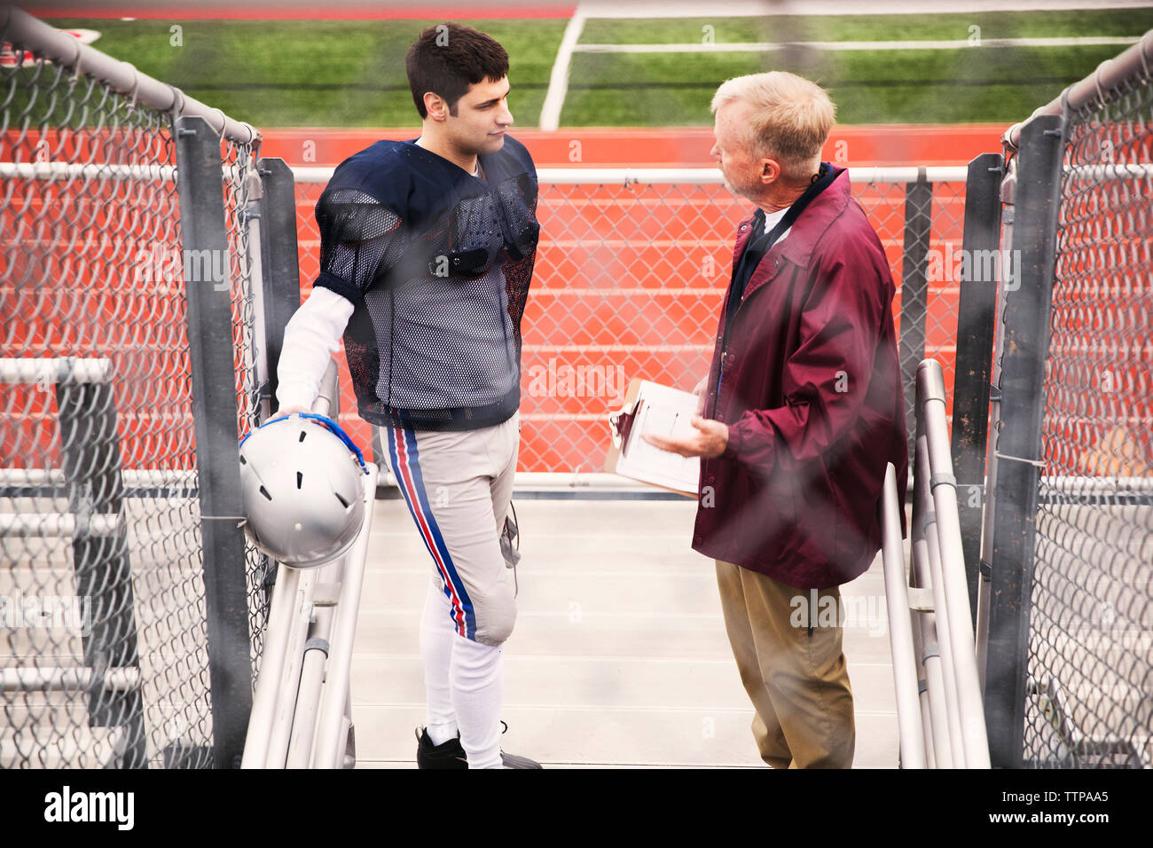 High angle view of coach discussing with American football player at stadium Stock Photo