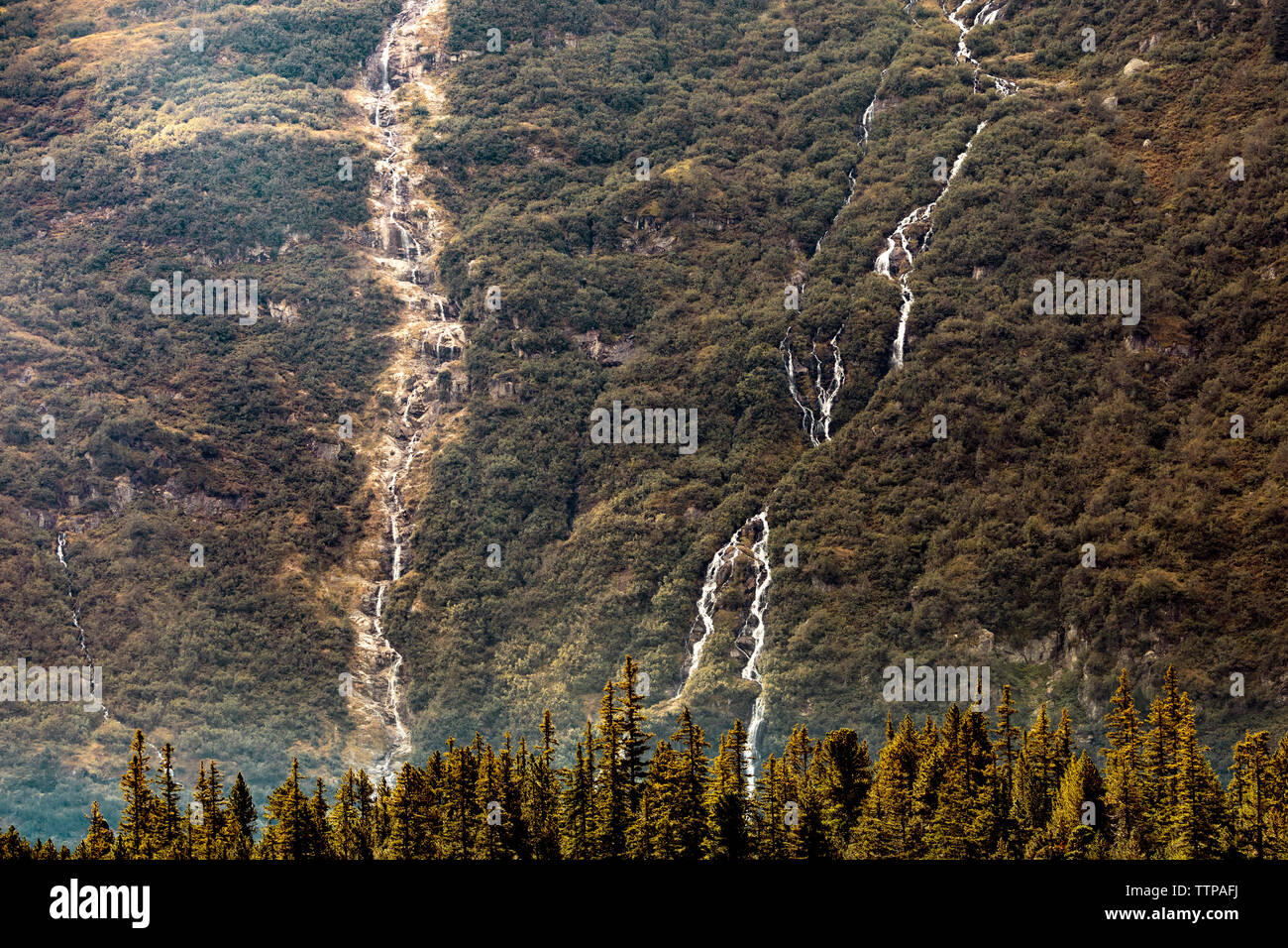 Distant view of waterfalls on green mountain Stock Photo