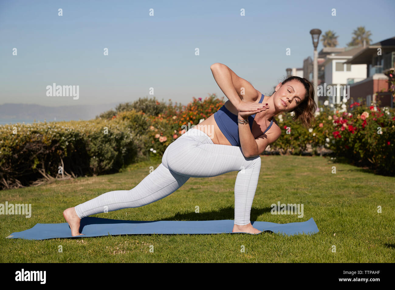 Full length of woman with legs apart and hands clasped practicing yoga on exercise mat Stock Photo