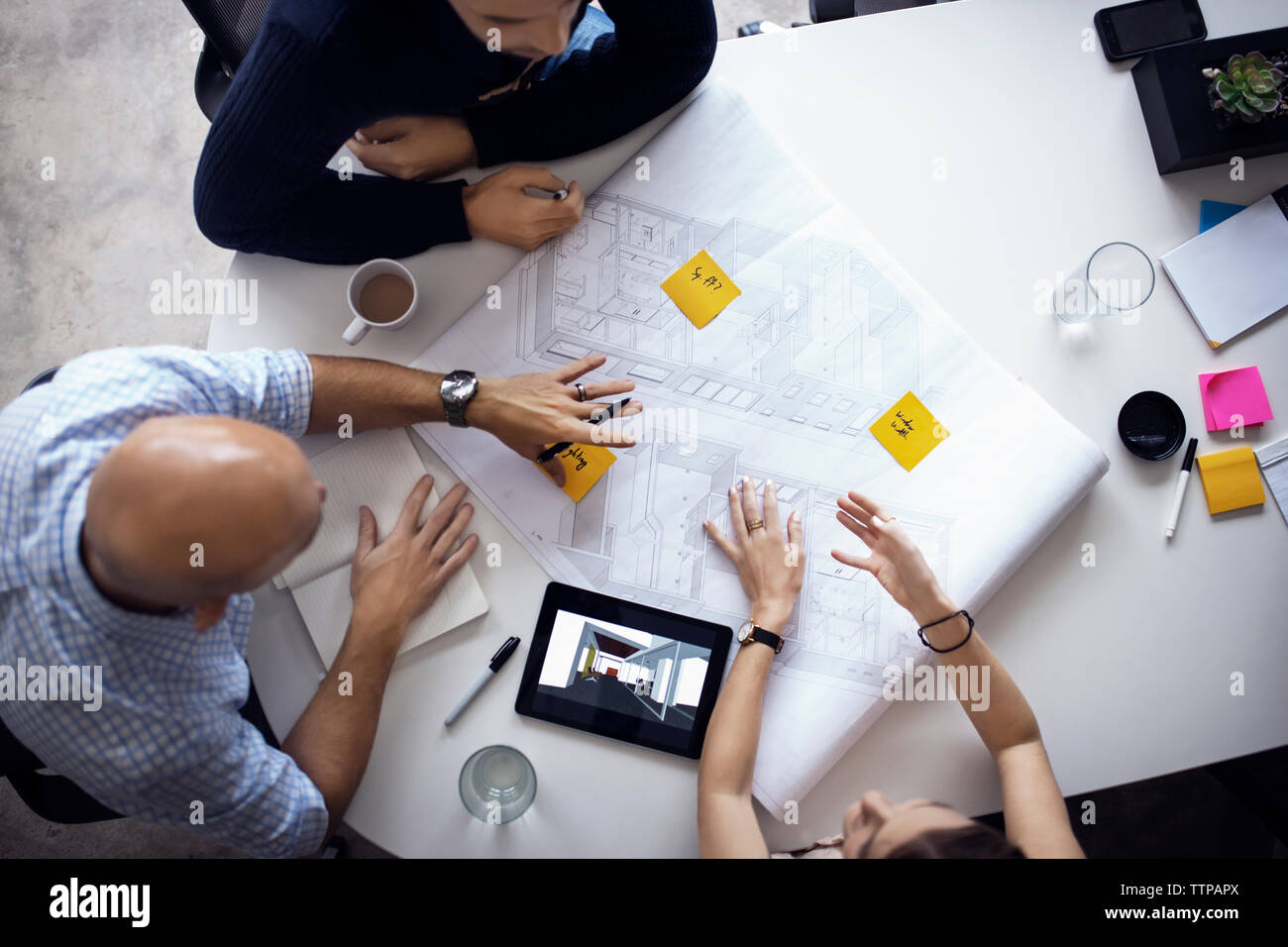 Overhead view of architects discussing over blueprints and digital tablet at creative office Stock Photo