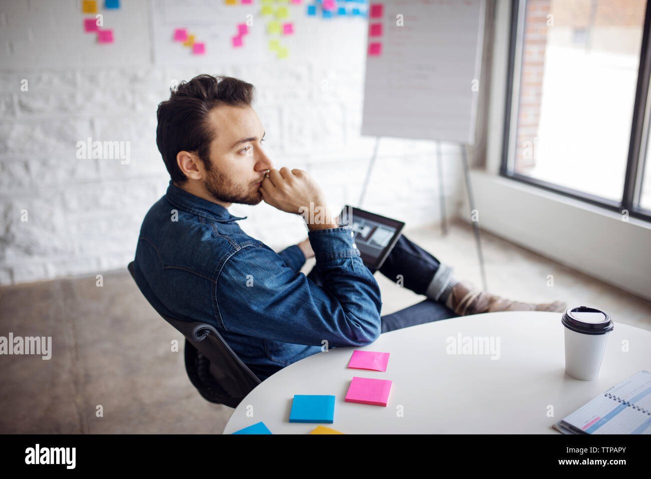Thoughtful businessman using tablet while sitting at creative office Stock Photo